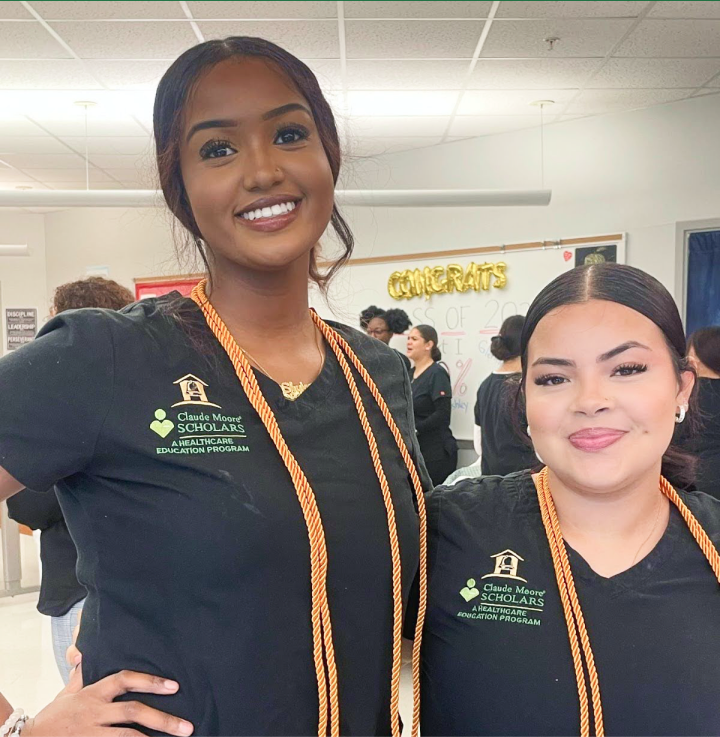 Two Claude Moore Scholars students in black scrubs with honor cords